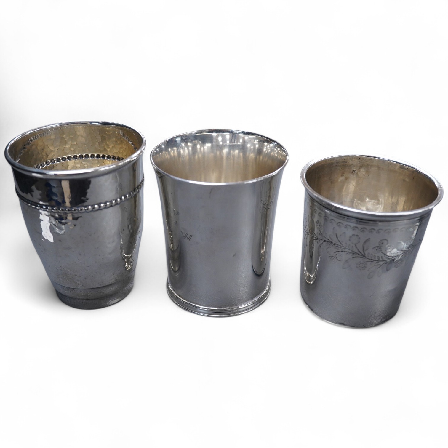 An Elizabeth II silver beaker, with engraved initials, makers TW over BD, London, 1992, 87mm, together with a 1920's hammered Danish white metal beaker and a 19th century French 950 standard white meal beaker, 9.8oz.